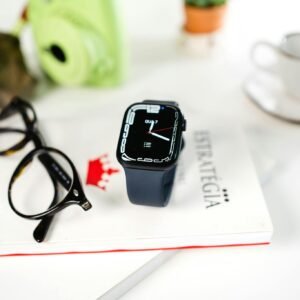 Close-up of a smartwatch and eyeglasses on a book, highlighting modern technology and style.