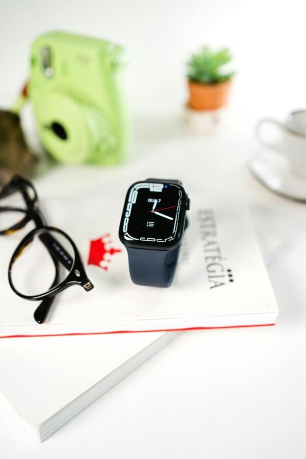 Close-up of a smartwatch and eyeglasses on a book, highlighting modern technology and style.
