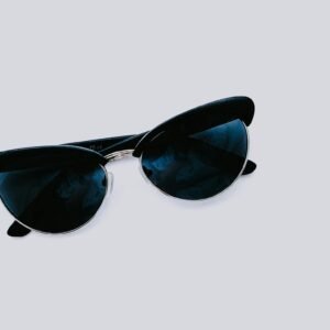From above of trendy sunglasses with dark lenses and creative design placed on clear white background in modern light studio