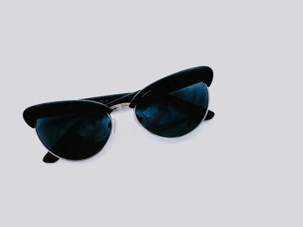 From above of trendy sunglasses with dark lenses and creative design placed on clear white background in modern light studio