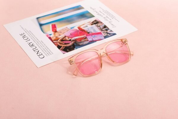 Pink sunglasses on a magazine page with a soft pastel background, capturing a chic and modern vibe.